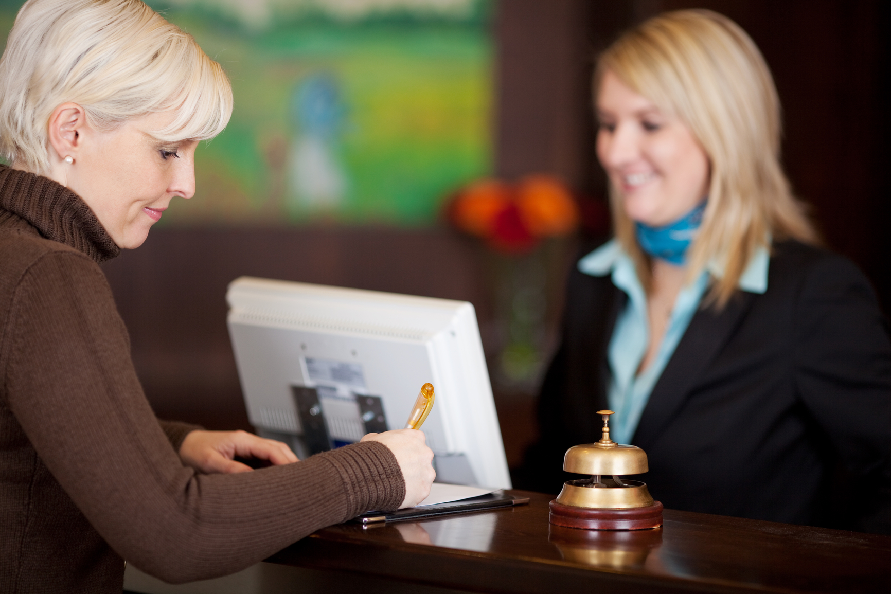 female guest filling up a formular at hotel counter